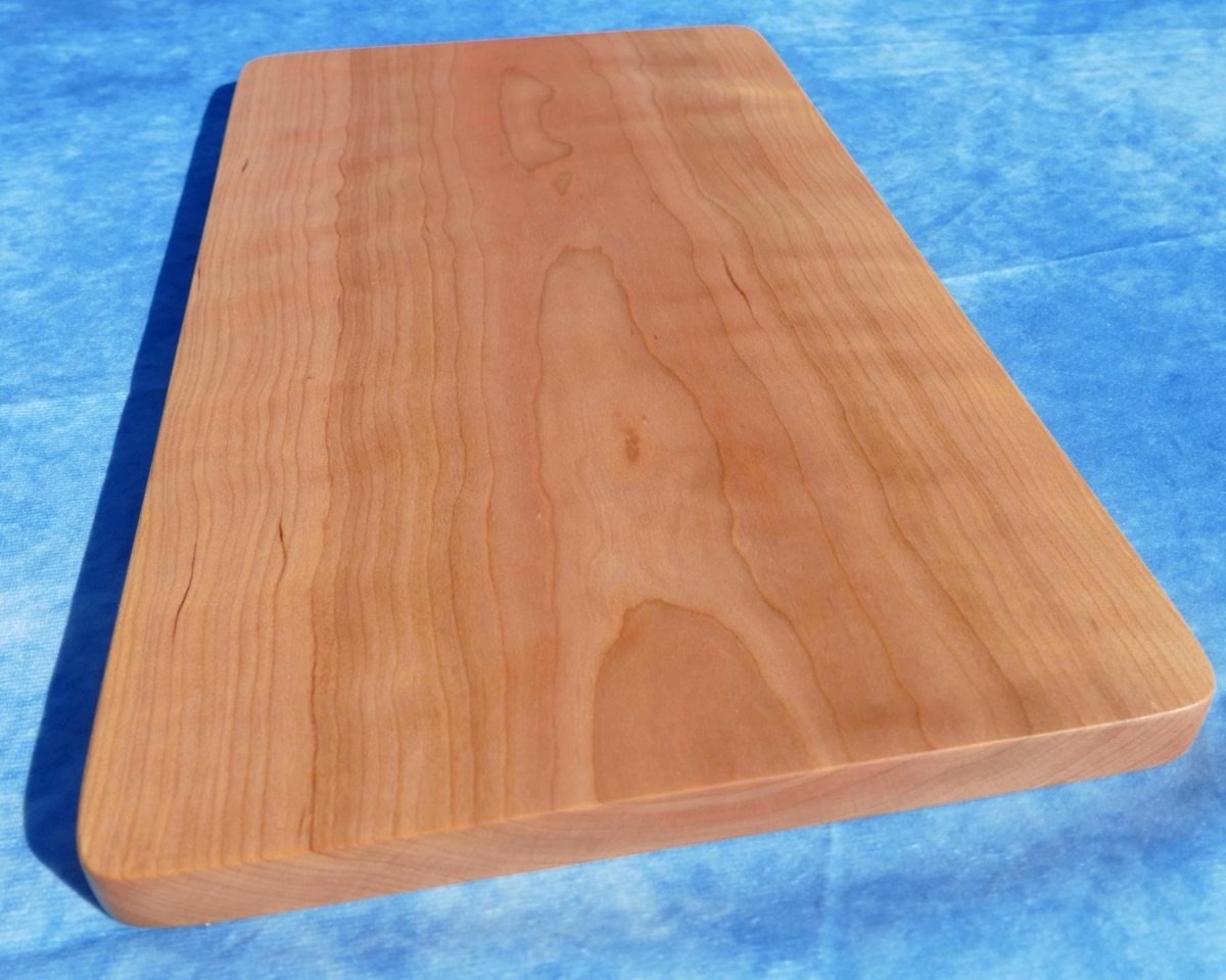 curly cherry hardwood cutting board on a blue background