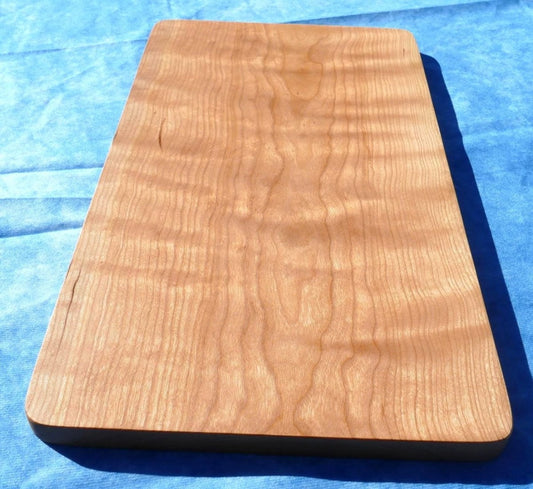 curly cherry hardwood cutting board on a blue background