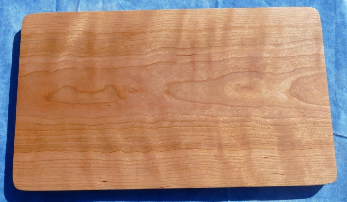 curly cherry hardwood cutting board on a blue background