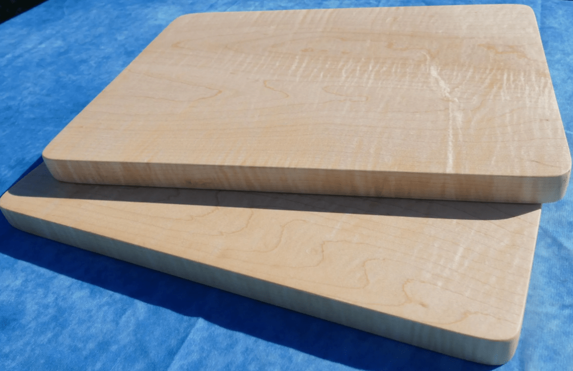 2 curly hard maple cutting boards with a blue background stacked over each other