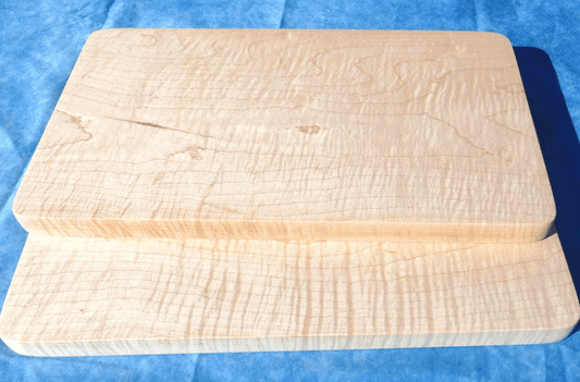 2 curly hard maple cutting boards with a blue background stacked over each other