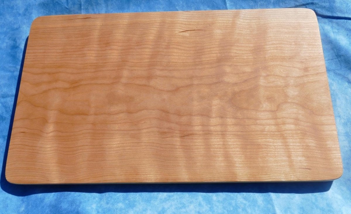 curly cherry hardwood cutting board on a blue background