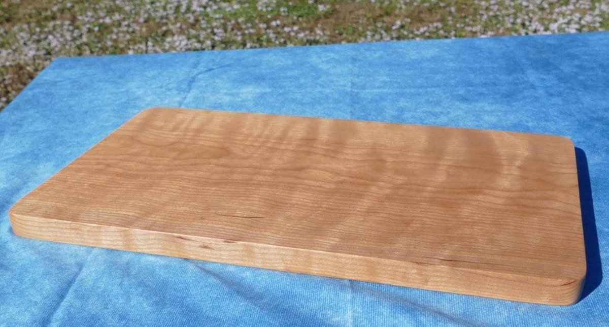 curly cherry hardwood cutting board on a blue background
