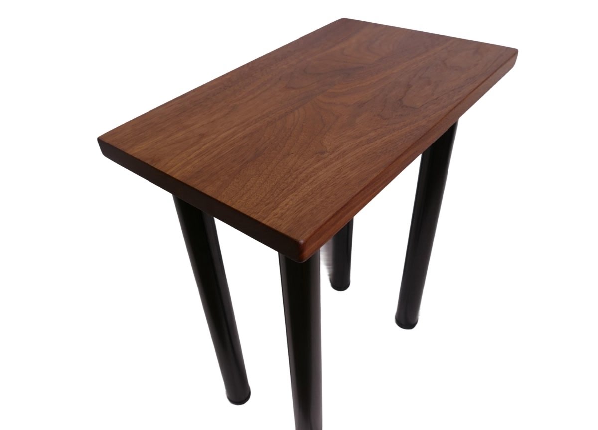 a black walnut table with round black metal legs on a white background