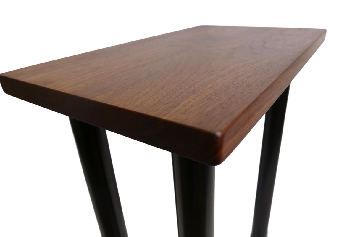 a black walnut table with round black metal legs on a white background