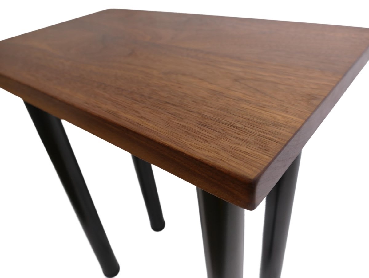 a black walnut table with round black metal legs on a white background