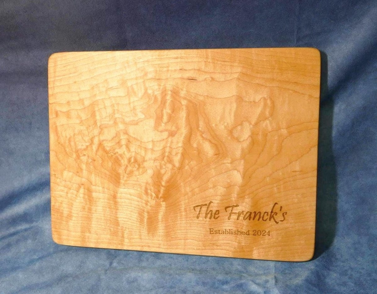 personalized, engraved, wooden cutting board made from hard curly maple hardwood on a blue background