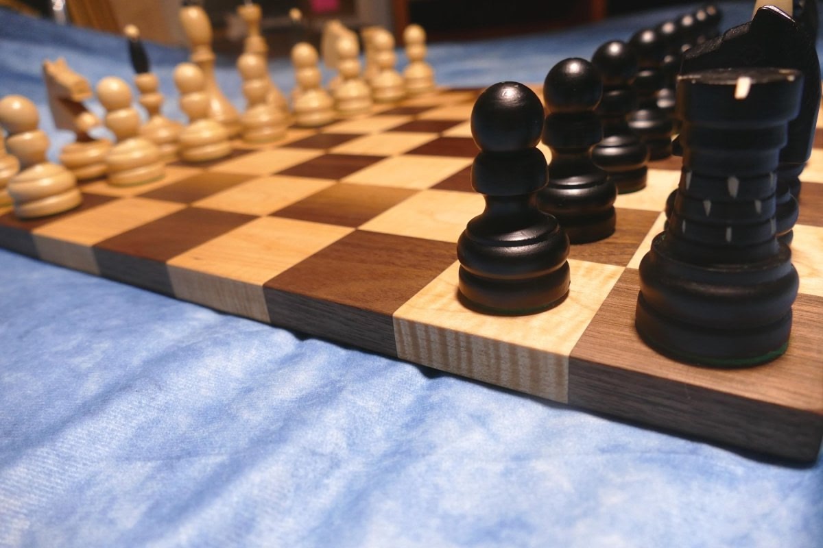 a wooden chess board with black pieces on it