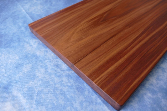 black walnut cutting board on a blue background