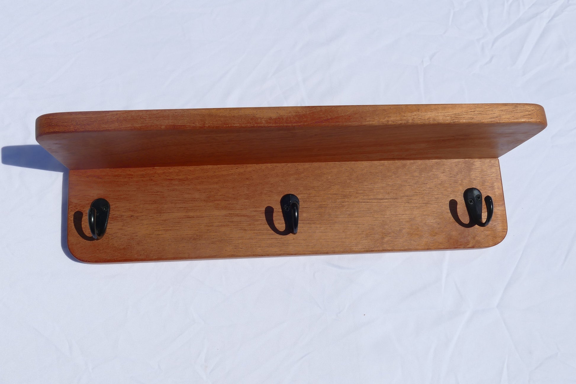 Mahogany coat rack with black hooks and a shelf
