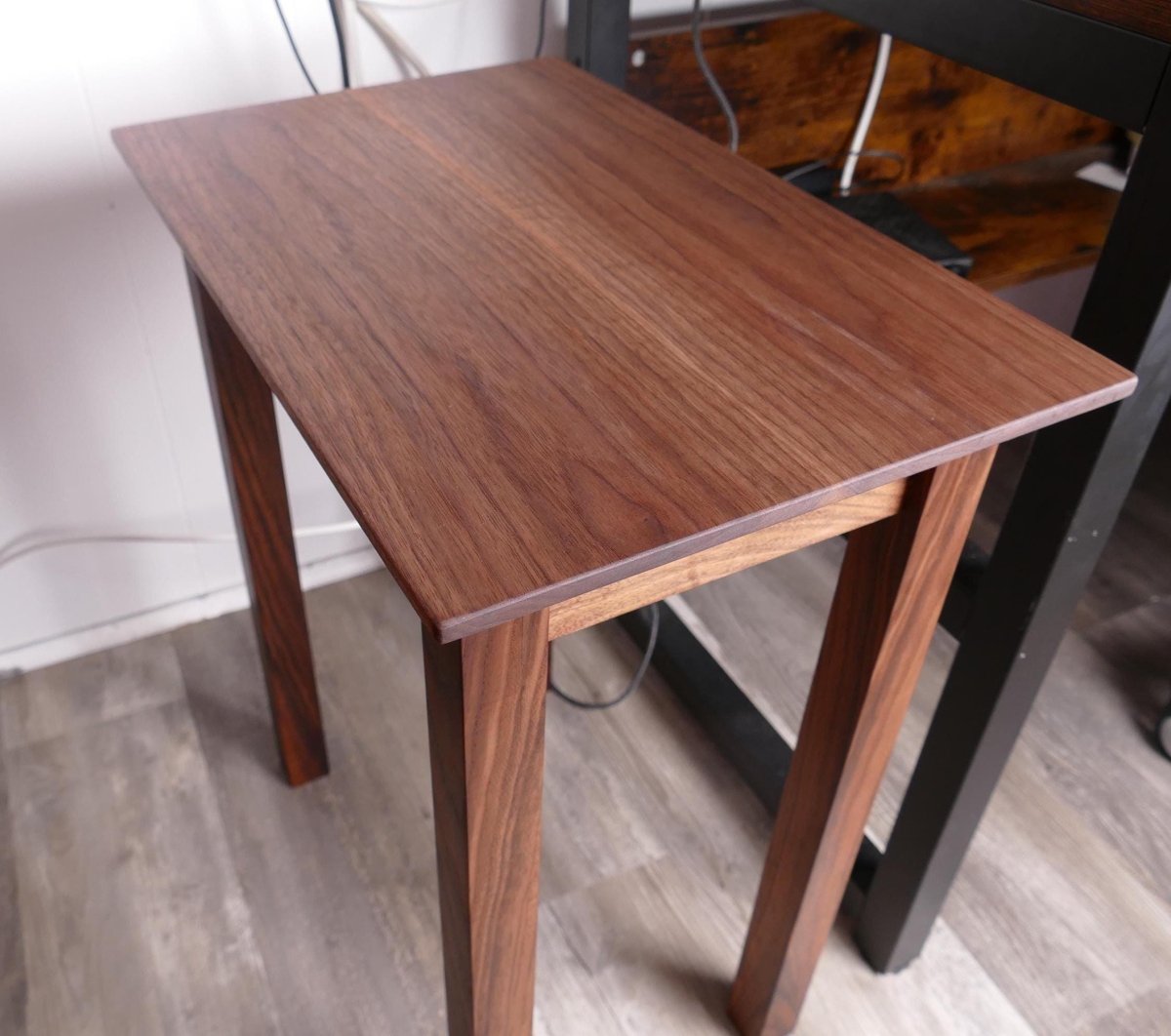 a wooden side table with a dark finish, placed on a wooden floor.