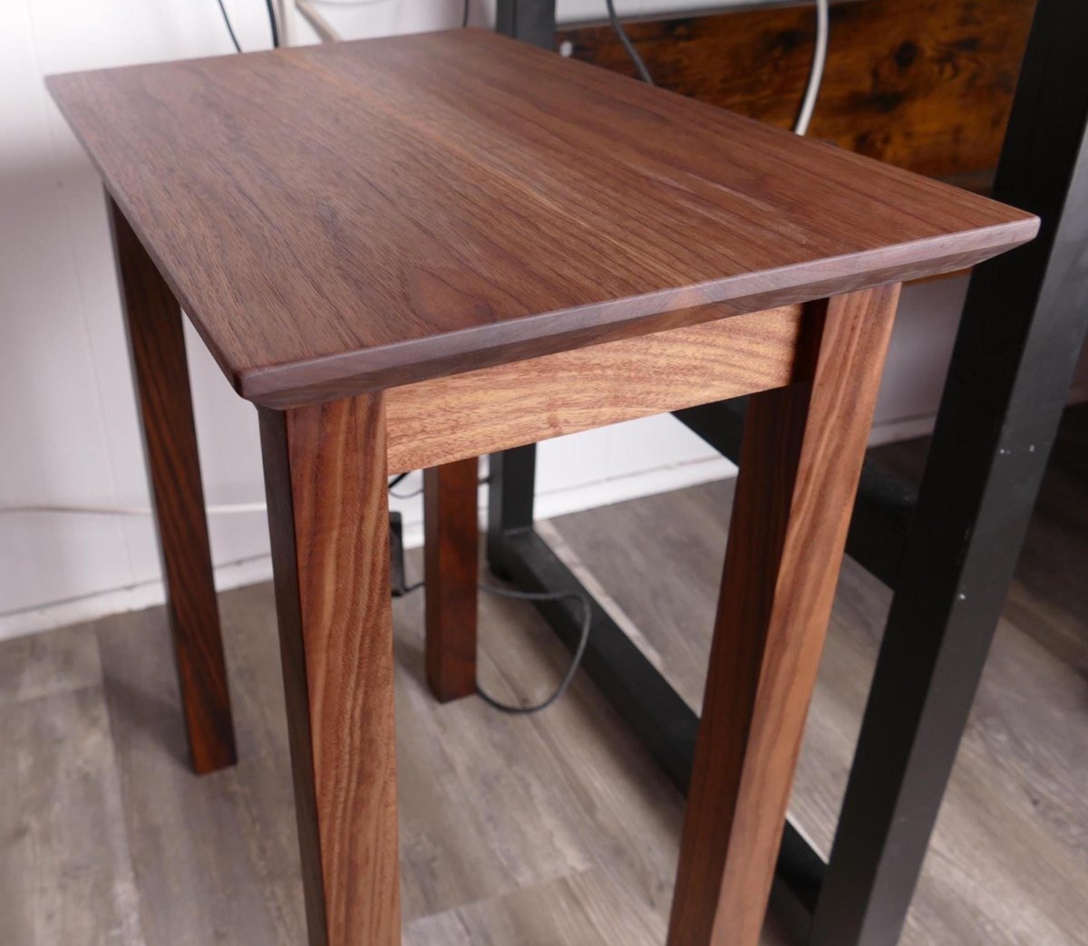 a wooden table with a dark finish, situated in a room with a wooden floor and a black metal frame.