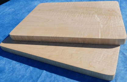 2 curly hard maple cutting boards with a blue background stacked over each other