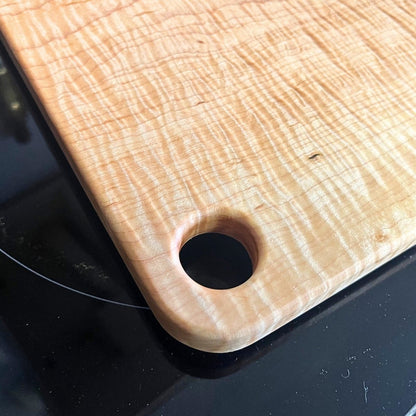curly maple cutting board with finger hole