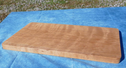 curly cherry hardwood cutting board on a blue background