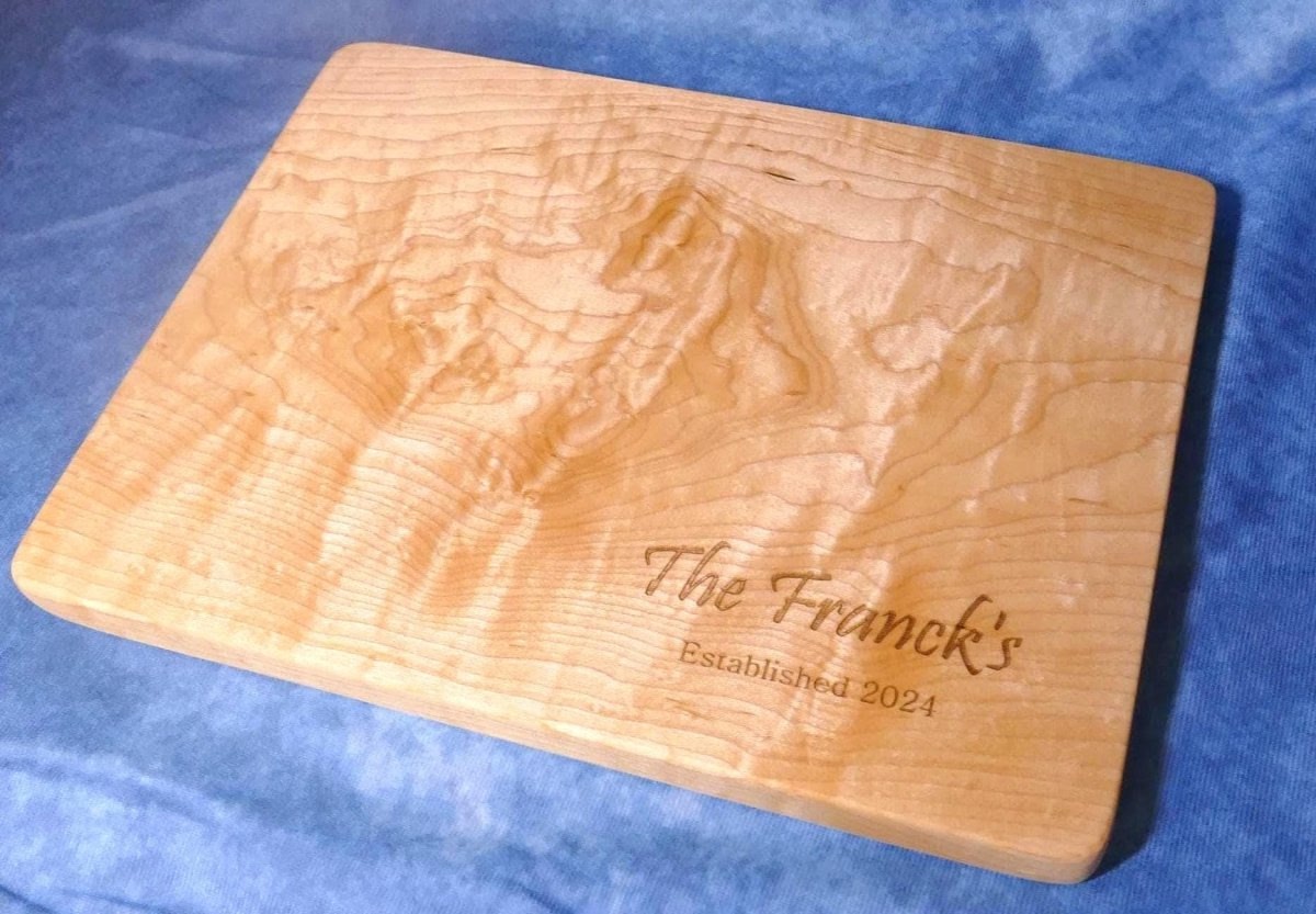 personalized, engraved, wooden cutting board made from hard curly maple hardwood on a blue background