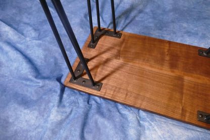 A close up of the bottom of the black walnut table upside down, with the hairpin legs attachment visible.